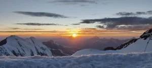 Breathtaking Monte Rosa panorama at 4,554 meters, showcasing snow-capped peaks, sprawling glaciers, and rugged alpine terrain under a vast blue sky in the Italian Alps. i rifugi per acclimatarsi prima di salire sul monte rosa